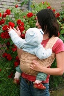 picture of baby in a sling with mom looking at flowers on baby sign language website