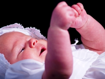 picture of an infant using sign language in white clothes and hat