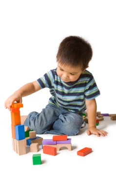 photograph of little toddler boy in a striped shirt, building blocks displaying the idea of home activities for toddlers