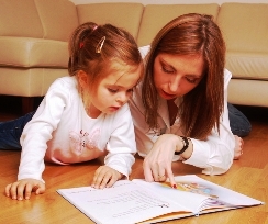 A picture of a mom and a three year old learning from a home schooling book